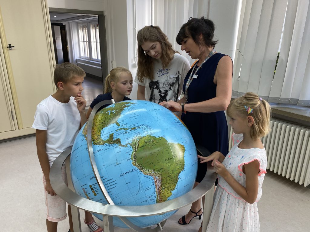 Kinder bestaunen einen großen Globus.