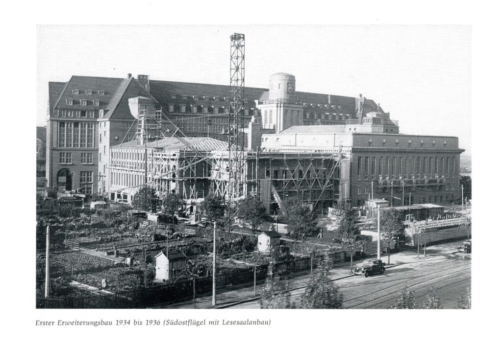 Historische Aufnahme des ersten Erweiterungsbaus mit Geräuten und einem Krahn. An der Rückseite der Rotunde ist die Uhr zu sehen.