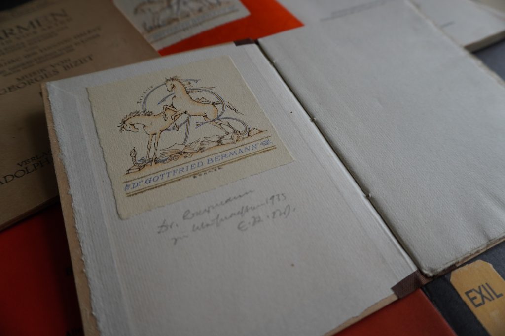 aufgeschlagenes buch mit dem Exlibris von Gottfried Bermann Fischer, das zwei Pferde zeigt, die durch die Buchstaben G und B springen. Unter dem Exlibris findet sich die handschriftliche Widmung "Dr. Bermann zu Weihnachten 1935. E. R. W."