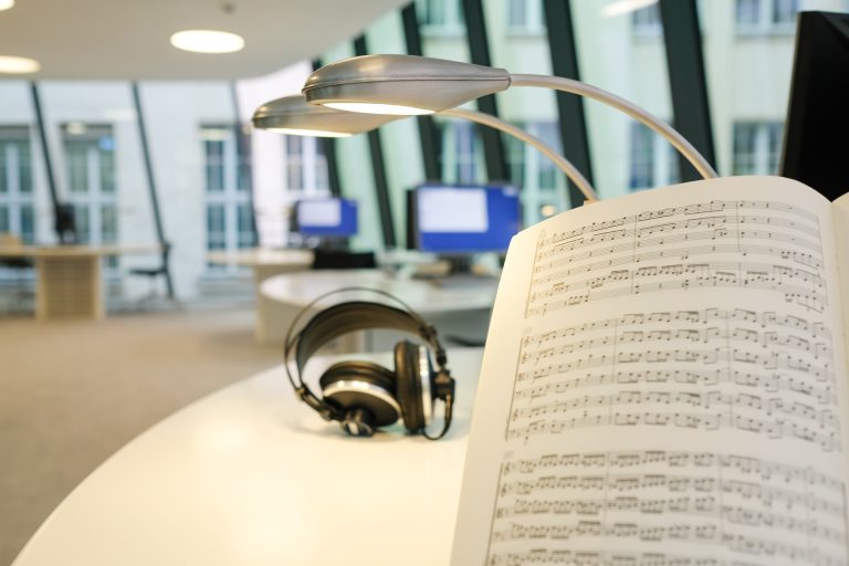 Noten und ein Kopfhörer auf einem Tisch in einem Lesesaal