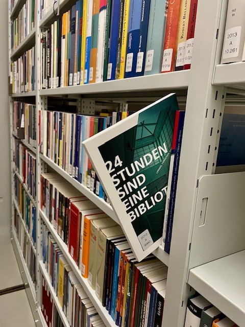 Das Buch 24 Stunden sind eine Bibliothek schaut aus dem Regalreihen des Büchermagazins heraus