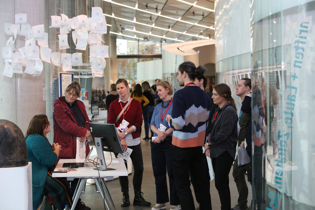 In einer modernen Ausstellung steht eine Gruppe von Menschen, die sich eine Präsentation ansehen