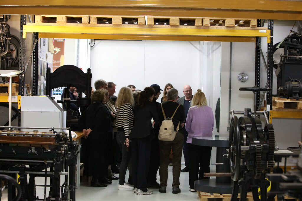 Eine Gruppe Menschen wird durch eine historische Ausstellung geführt