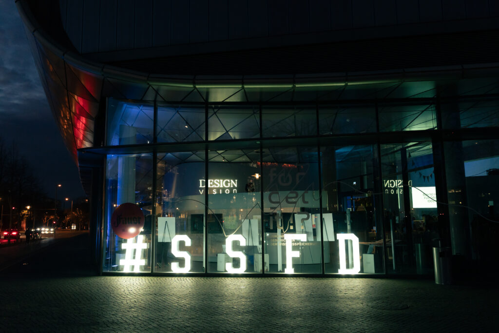 Eine Glasfassade ist beleuchtet von großen Buchstaben SSFD.