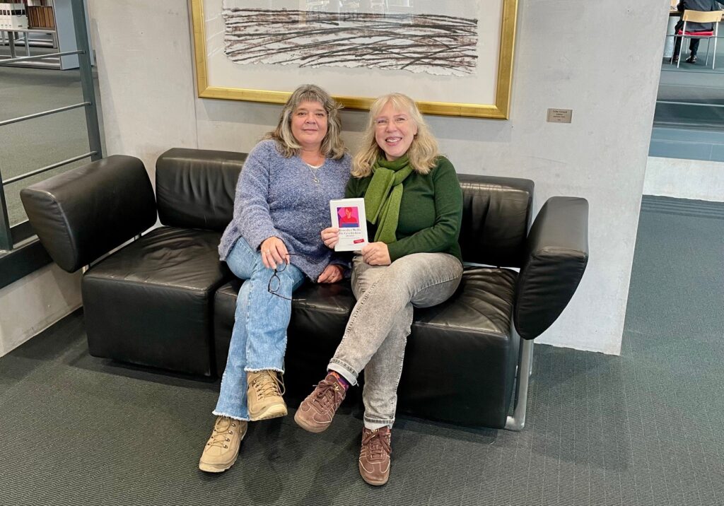 Die Beitragsautorinnen mit einem Buch auf einem Sofa in der DNB Frankfurt