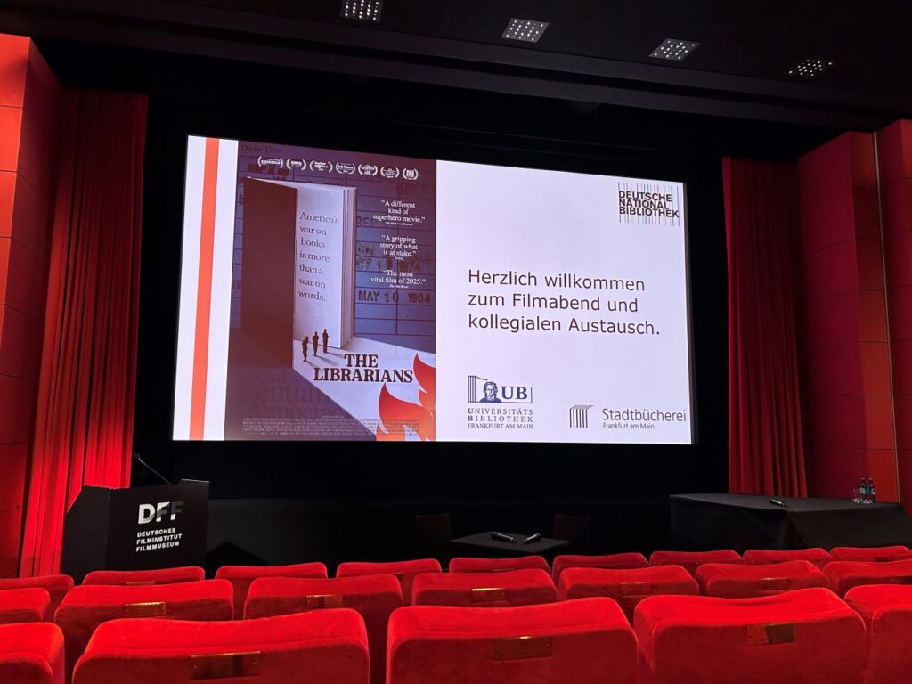 Blick über die Kinosessel auf die Leinwand mit dem Filmplakat und der Begrüßung des Publikums