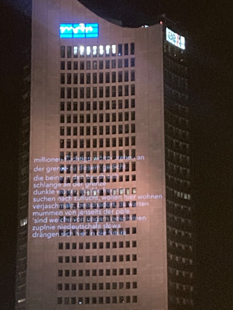 Ein hohes Gebäude wird mit Text aus Licht angestrahlt