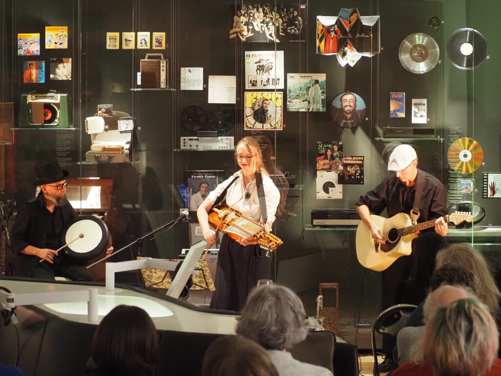 Band mit drei Musikern vor einer Vitrine