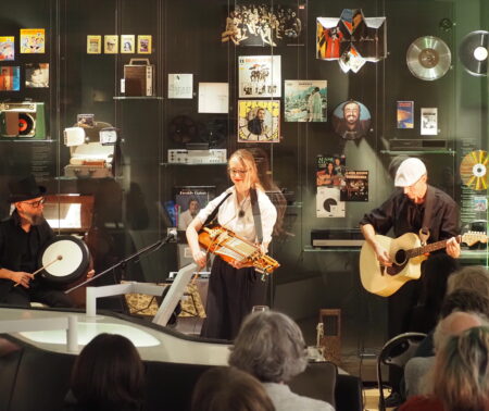Band mit drei Musikern vor einer Vitrine