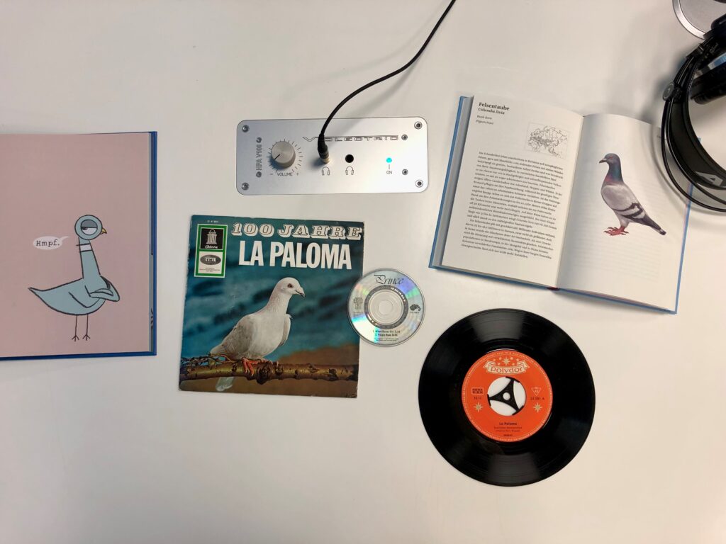 Tonträger aus dem Bestand des Deutschen Musikarchivs und Bücher aus dem Bestand der Deutschen Nationalbibliothek liegen mit Kopfhörern auf einem Tisch im Musiklesesaal der DNB in Leipzig