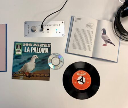 Tonträger aus dem Bestand des Deutschen Musikarchivs und Bücher aus dem Bestand der Deutschen Nationalbibliothek liegen mit Kopfhörern auf einem Tisch im Musiklesesaal der DNB in Leipzig