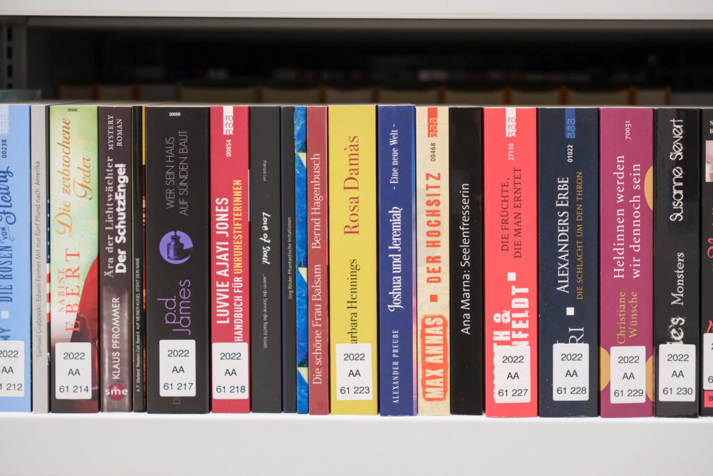 Das Bild zeigt ein Regal des Magazins der Deutschen Nationalbibliothek Frankfurt am Main. Man sieht verschiedene Buchrücken in unterschiedlichen Farben und breiten.