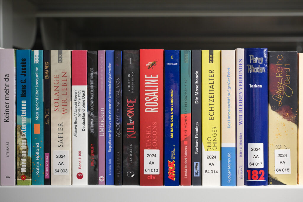 Das Bild zeigt ein Regal des Magazins der Deutschen Nationalbibliothek Frankfurt am Main. Man sieht verschiedene Buchrücken in unterschiedlichen Farben und breiten.