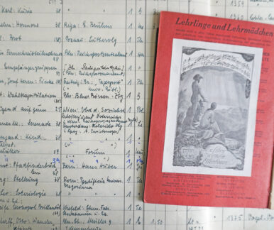 Auf einer Seite aus dem Zugangsbuch der Deutschen Bücherei Leipzig liegt ein aufgeschlagenes Buch, in dessen Vorsatz das Exlibris von Wilhelm Ellenbogen eingeklebt ist.