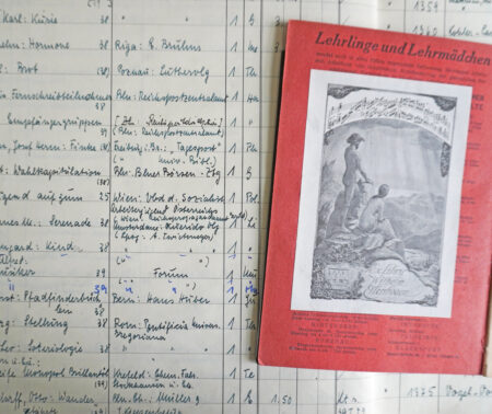 Auf einer Seite aus dem Zugangsbuch der Deutschen Bücherei Leipzig liegt ein aufgeschlagenes Buch, in dessen Vorsatz das Exlibris von Wilhelm Ellenbogen eingeklebt ist.