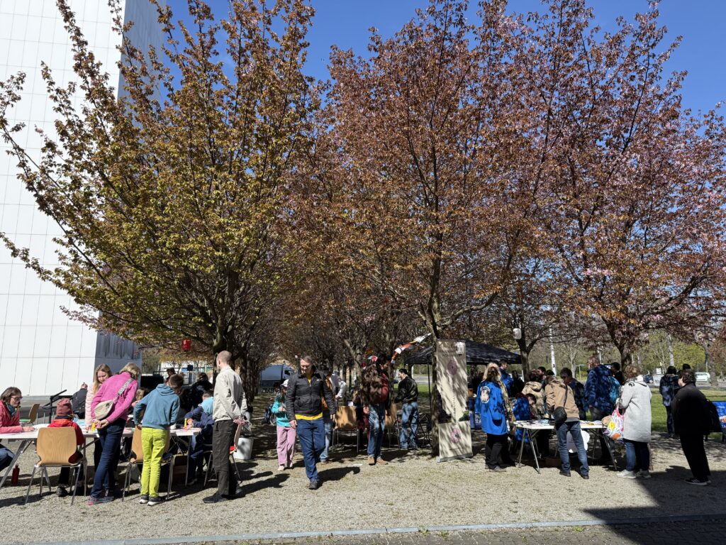 Mehrere Stände unter Kirschbäumen, die noch vereinzelte Blüten haben