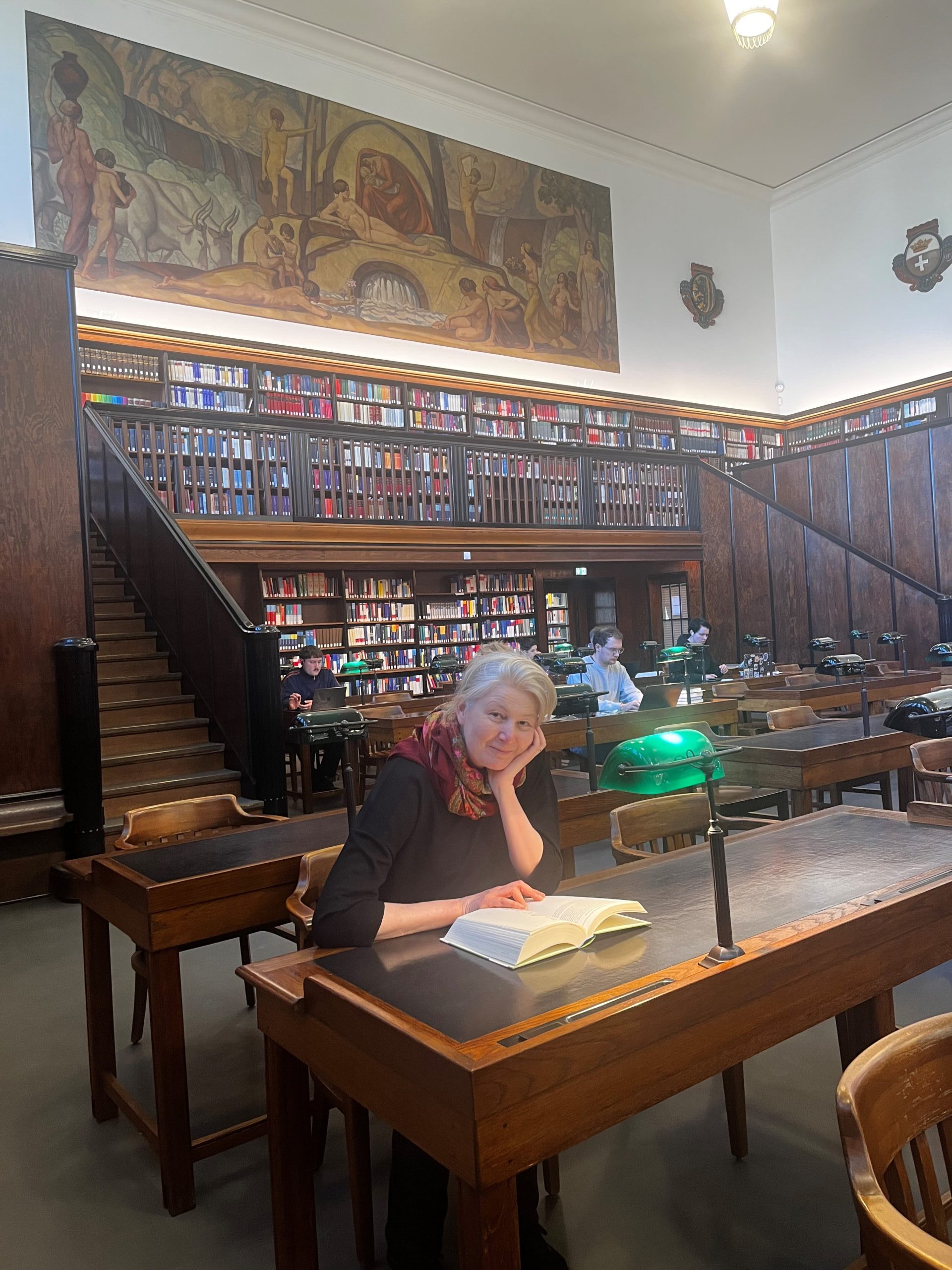 Gerda Raidt mit Buch an einem Arbeitsplatz im Großen Lesesaal.