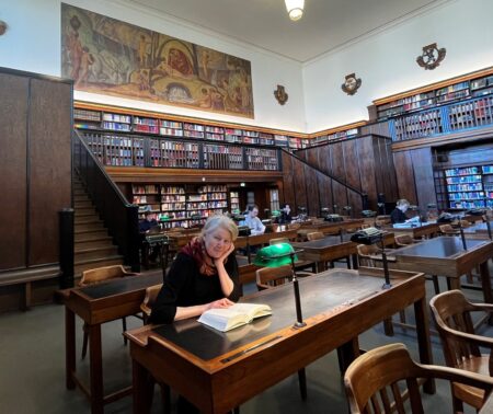 Gerda Raidt mit Buch an einem Arbeitsplatz im Großen Lesesaal.
