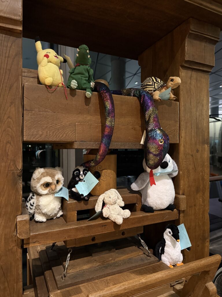 Auf der Nachbildung einer historischen Druckerpresse sitzen viele Kuscheltiere.