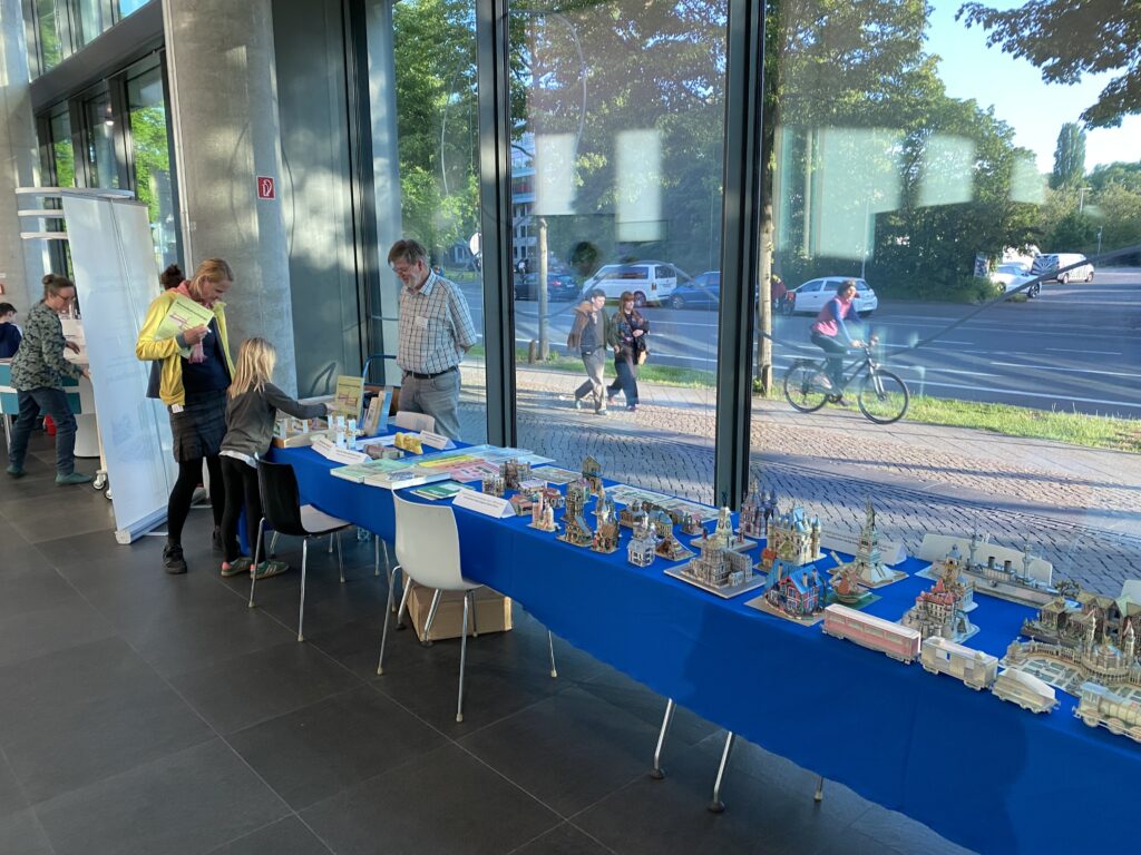 Langer Tisch mit verschiedenen Häuser-Modellen aus Karton