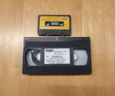 Eine Kompaktkassette und eine VHS-Kassette auf einem Tisch.