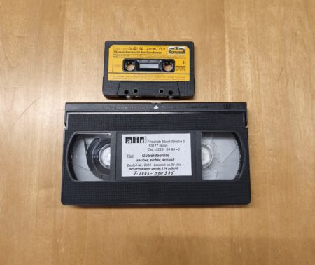 Eine Kompaktkassette und eine VHS-Kassette auf einem Tisch.