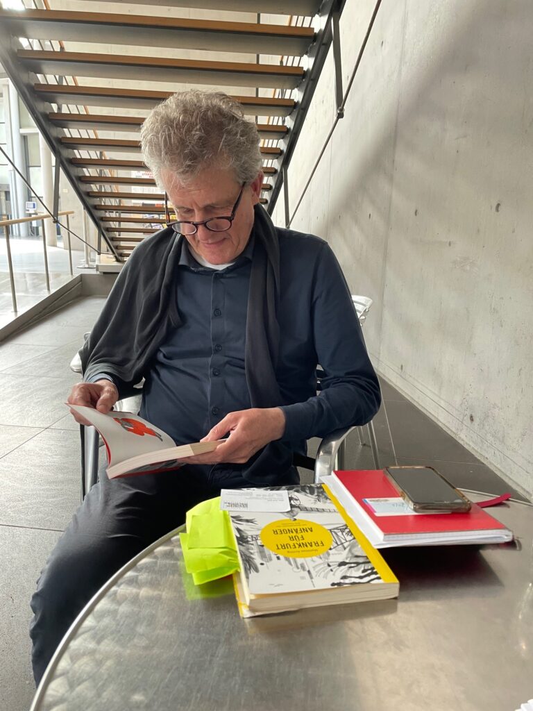 Matthias Arning sitzt mit Büchern im Bibliothekscafé