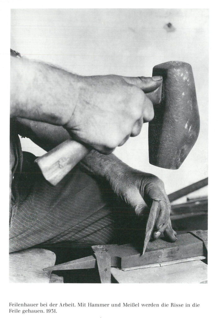 Schwarzweißbild mit einer Hand, die einen Hammer hält.um eine Feile zu behauen
