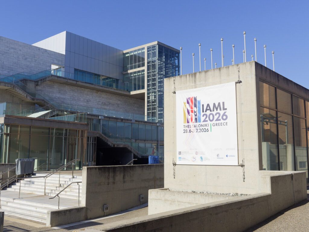 An einer Mauer der Konzerthalle Thessaloniki prangt ein Banner, das auf den IAML-Kongress hinweist.