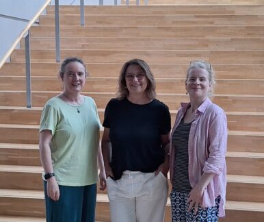 3 Personen stehen vor einer großen Treppe
