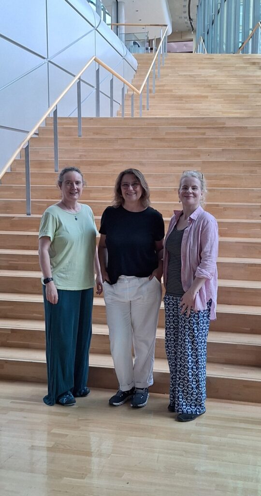 3 Personen stehen vor einer großen Treppe