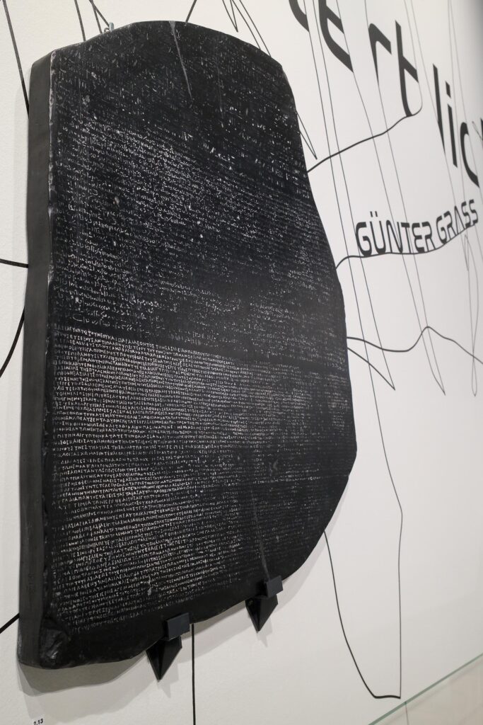 Stein von Rosetta an einer mit Schrift versehenen Wand montiert
