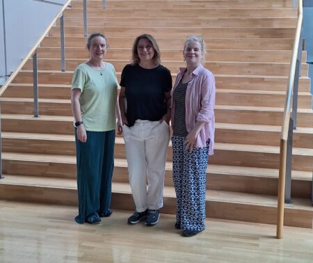 3 Personen stehen vor einer großen Treppe
