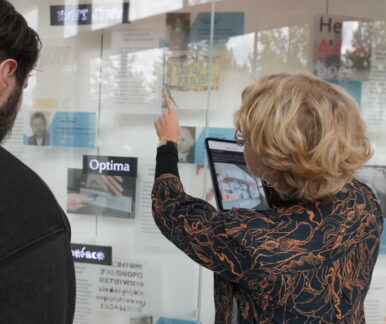 Eine junge Frau zeigt einem jungen Mann etwas in der Ausstellungsvitrine. Vermittlungsarbeit