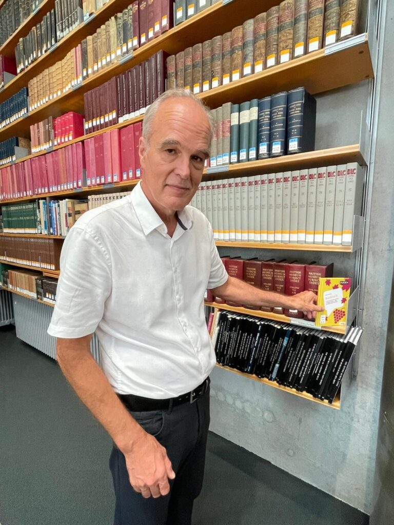 Der Autor Frank Winter mit seinem Buch Badisch vor einer Bücherwand