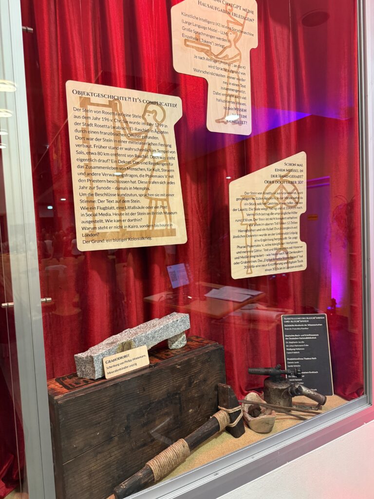 Vitrine mit Ausstellungstexten, Steinwerkzeugen und einem Stück Granodiorit